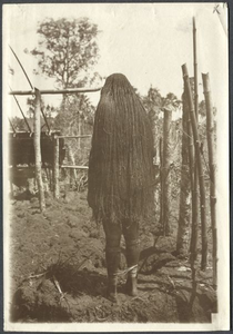 229251 Vrouw van de Marind-anim poseert in een omgeploegd veld. Achteraanzicht